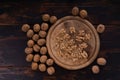 Cracked and whole walnuts on round wooden plate and wooden table, top view. Healthy nuts and seeds composition. Royalty Free Stock Photo