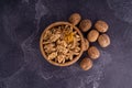 Cracked and whole walnuts in wooden bowl and on dark slate surface. Healthy nuts and seeds composition. Royalty Free Stock Photo