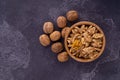 Cracked and whole walnuts in wooden bowl and on dark slate surface. Healthy nuts and seeds composition. Royalty Free Stock Photo