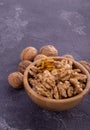 Cracked and whole walnuts in wooden bowl and on dark slate surface. Healthy nuts and seeds composition. Royalty Free Stock Photo