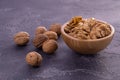 Cracked and whole walnuts in wooden bowl and on dark slate surface. Healthy nuts and seeds composition. Royalty Free Stock Photo