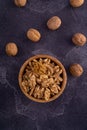 Cracked and whole walnuts in wooden bowl and on dark slate surface. Healthy nuts and seeds composition. Royalty Free Stock Photo