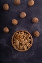 Cracked and whole walnuts in wooden bowl and on dark slate surface. Healthy nuts and seeds composition. Royalty Free Stock Photo