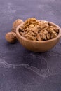 Cracked and whole walnuts in wooden bowl and on dark slate surface. Healthy nuts and seeds composition. Royalty Free Stock Photo