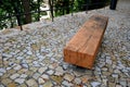 wooden massive park bench shape block with metal legs on granite natural cobblestone irregular brown gray pavement on pedestrian