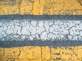 Cracked yellow and white paint lines on grey asphalt road texture, top view as grunge background or wallpaper Royalty Free Stock Photo