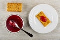 Crackers with flax seeds, spoon in bowl with cherry jam, cracker poured jam in plate on wooden table. Top view Royalty Free Stock Photo