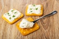 Crackers with soft cheese, greens, spoon with cheese on cookie on table Royalty Free Stock Photo