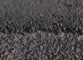 Cracking asphalt or imperfect asphalt patch on the edge. Full of small stone and sand.