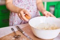 Cracking an egg to a flour. Close-up of woman`s hands breaks an egg for pastry Royalty Free Stock Photo