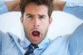 Cracking under the pressure. Portrait of a young businessman shouting with hands behind his head.