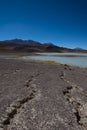 Cracks in the dry desert sand leading the eye to the green Laguna Honda Royalty Free Stock Photo