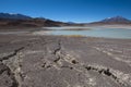 Cracks in the dry desert sand leading the eye to the green Laguna Honda Royalty Free Stock Photo