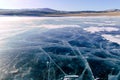 Cracks on the surface of the blue ice. Frozen lake in winter mountains on Lake Baikal