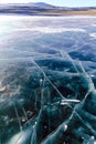 Cracks on the surface of the blue ice. Frozen lake in winter mountains on Lake Baikal