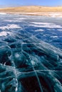 Cracks on the surface of the blue ice. Frozen lake in winter mountains on Lake Baikal