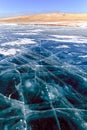 Cracks on the surface of the blue ice. Frozen lake in winter mountains on Lake Baikal