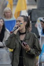 Woman with face paint speaking to microphone on an anti-war rally