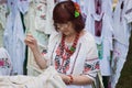 Craft art embroidery, woman decorates fabric with color thread, handmade shirt with ornament