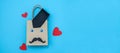 Craft bag with tie, paper mustache and hearts on a blue background. Royalty Free Stock Photo