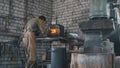 Craft - beard muscular man working on a blacksmith with metal