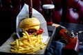 Craft beef burger and french fries on table in restaurant with glass of beer on dark background. Modern fast food lunch Royalty Free Stock Photo