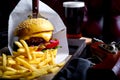 Craft beef burger and french fries on table in restaurant with glass of beer on dark background. Modern fast food lunch Royalty Free Stock Photo