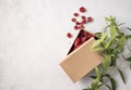 Craft box with red dry flowers on a gray textured background with branch plant. The concept of ecological packaging and zero waste Royalty Free Stock Photo