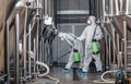 Craft brewery, eco product and disinfection. Workers in hazmat suits clean plant
