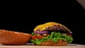 Craft burger is cooking on black background. Consist: sauce, lettuce, tomato, red onion, pickle, cheese, bacon, air bun Royalty Free Stock Photo