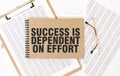 Craft colour notepad with text SUCCESS IS DEPENDENT ON EFFORT. Notepad with eyeglasses and text documents. Business concept Royalty Free Stock Photo
