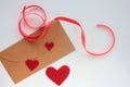 Craft envelop with Red fabric hearts and red ribbon on white background. Valentine`s day greeting card.