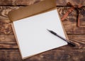 Craft envelop, white paper into it  and black pencil  on old brown wooden  table Royalty Free Stock Photo