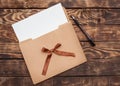 Craft envelop, white paper into it  and black pencil  on old brown wooden  table Royalty Free Stock Photo
