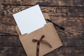 Craft envelop, white paper into it and black pencil on old brown wooden table Royalty Free Stock Photo