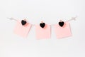 Craft hearts wooden black chalkboard clothespins on rope twine on white wall with pink paper note, horizontal. Garland decoration