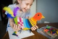 Craft with kids. bright bird, cut from cardboard and painted with wax crayons,in the hands of a child