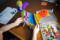 Craft with kids. bright bird, cut from cardboard and painted with wax crayons,in the hands of a child