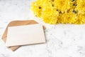 Craft kraft paper envelope and yellow chrysanthemum flowers on a light background. Flat workspace. Flat lay, top view