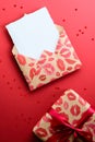 Craft paper envelope with lipsticks marks and gift box on red background with heart shaped confetti. Happy Valentine`s Day concep Royalty Free Stock Photo