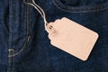 A craft paper tag label with copy space on dark blue jeans background with fore pocket, denim fashion background Royalty Free Stock Photo