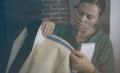 Craft workshop for tailoring. Young seamstress repairing a men`s light jacket, measuring the dimensions on a mannequin. Toning, Royalty Free Stock Photo