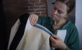 Craft workshop for tailoring. Young seamstress repairing a men`s light jacket, measuring the dimensions on a mannequin. Toning,