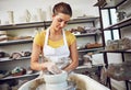 She crafted her hobby into a career. a young woman making a ceramic pot in a workshop.