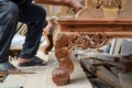 craftsman attaching legs to a handcarved wooden sofa frame