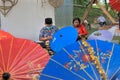 A craftsman couple is painting on a colorful umbrella,