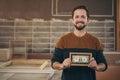 Craftsman entrepreneur proudly displaying a framed bank note