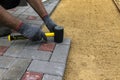 A craftsman in gloves with a rubber mallet lays concrete blocks on a gravelly sand base. Laying concrete blocks on the sidewalk Royalty Free Stock Photo