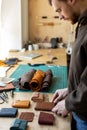 Craftsman hands laying out leatherwork on wooden table at leather workshop. Handwork accessories