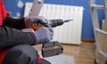 Craftsman holding a screwdriver drill ready to perform home renovation. Worker in work clothes on a construction site on an Royalty Free Stock Photo